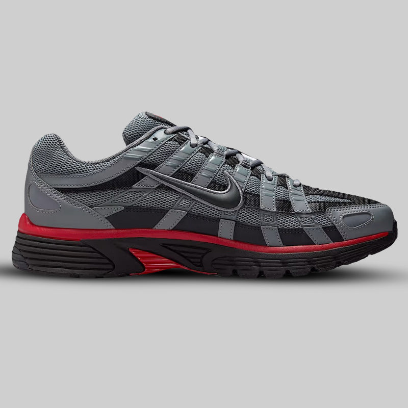 Gray and black athletic shoe with red sole on a gray background