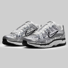 Pair of silver and gray Nike sneakers on a light gray background